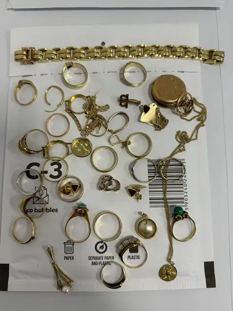 Kundenfoto: viele Goldschmuckstücke auf einem Versandumschlag, darunter Ringe, Ohrringe und ein Gliederarmband
