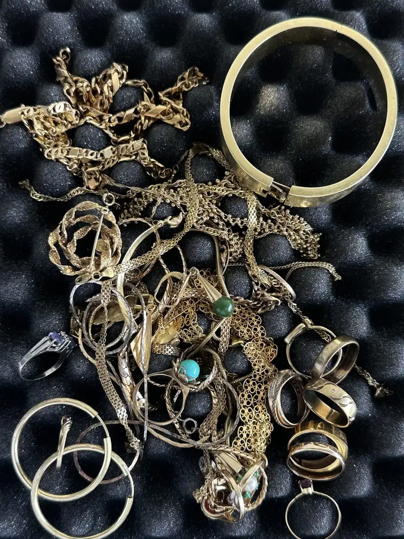 Kundenfoto: Goldschmuck mit Armreif, Ketten, Ringen und Creolen auf schwarzem Schaumstoff