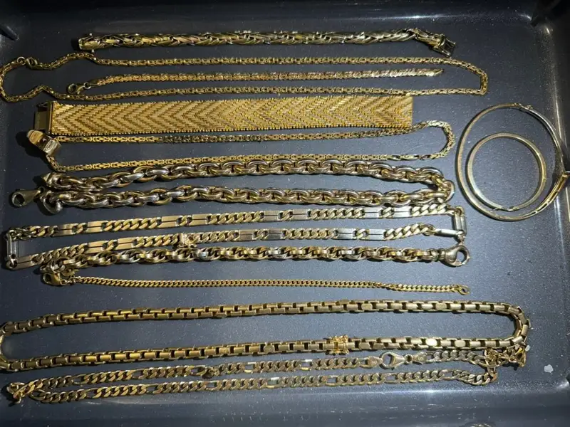 Kundenfoto: Sammlung aus Goldketten und Goldarmbändern auf einer dunklen Ablage